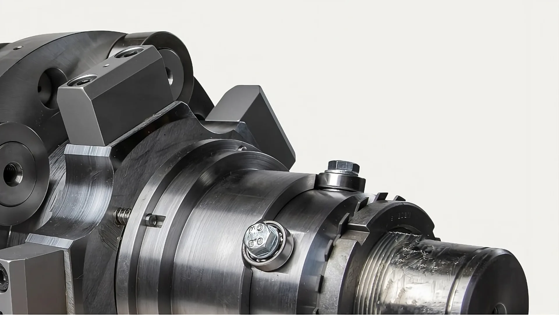 Close-up of a metallic machine component with bolts and cylindrical structures. The smooth, shiny surface conveys precision engineering and industrial function.