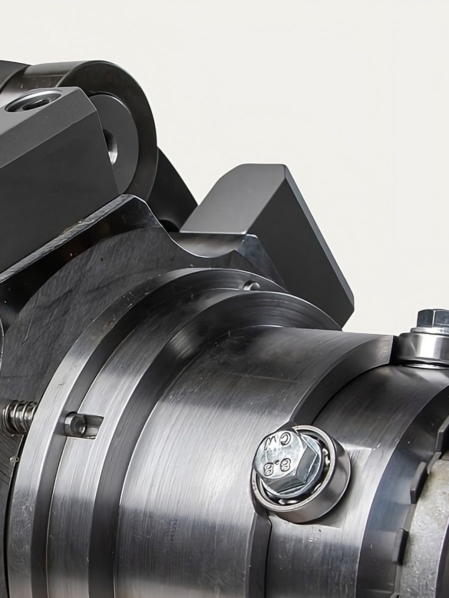 Close-up of a metallic machine component with smooth cylindrical shapes and bolts. The shiny surface and precision details convey industrial quality.