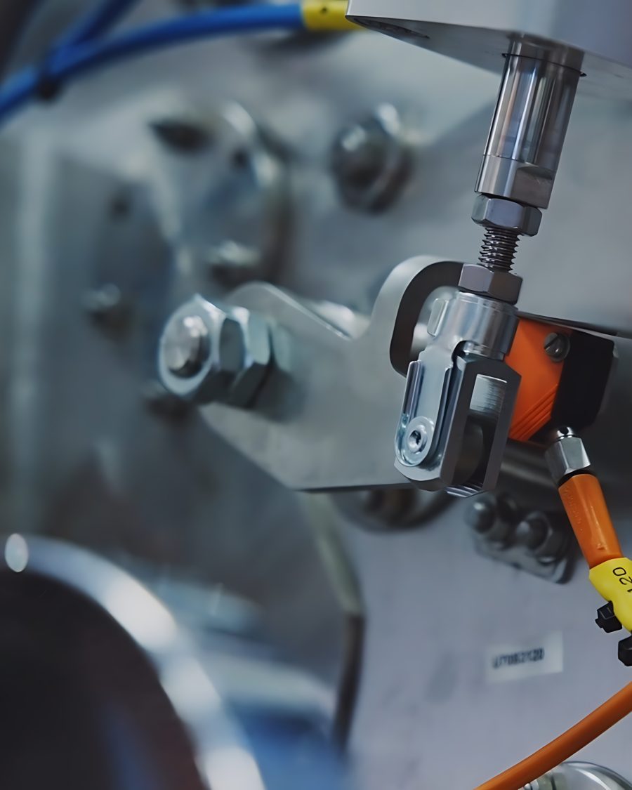 Close-up of industrial machinery featuring metal components, bolts, and colorful cables. The setting appears technical and precise, evoking innovation.