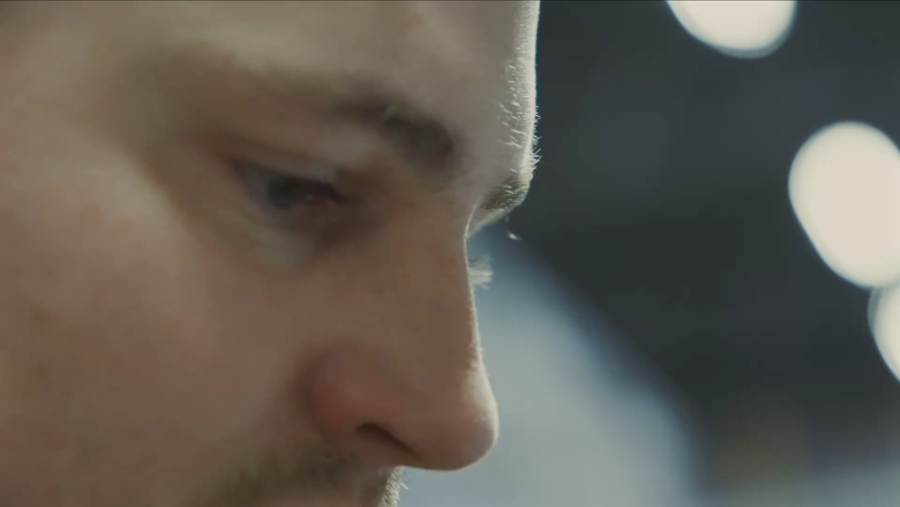 Close-up of a person's face in profile, focusing on the eyes and nose, with a thoughtful expression. Blurred lights create a soft, contemplative tone.